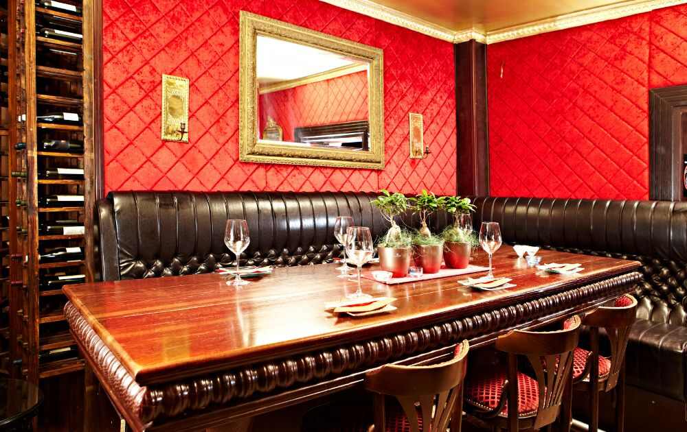 private room in restaurant with red walls, wood table, black couch